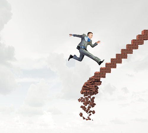 Young businessman walking up collapsing staircase representing success concept