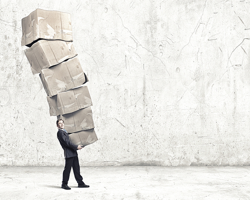 Businessman carrying big stack of carton boxes