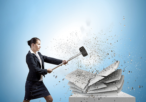 Businesswoman in anger crashing keyboard with hammer