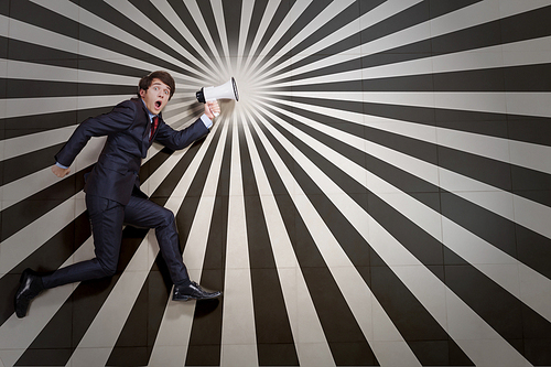 Young businessman running with megaphone in hand