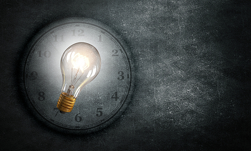 Conceptual image with light bulb and clock on dark background