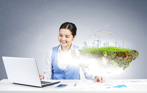 Young smiling businesswoman sitting at table and working with 3d ecology project