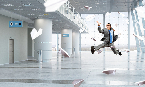 Happy young businessman running away from office