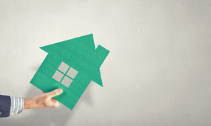 Hand of business person holding house card