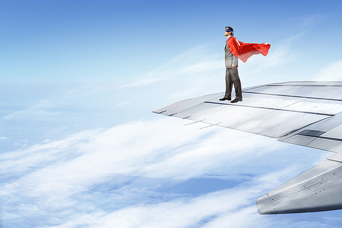 Super man standing on edge of airplane wing