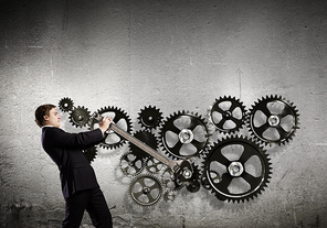 Young businessman fixing gears mechanism with wrench