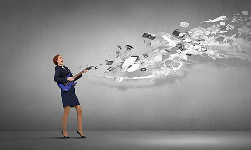 Cheerful businesswoman playing electric guitar on cement background