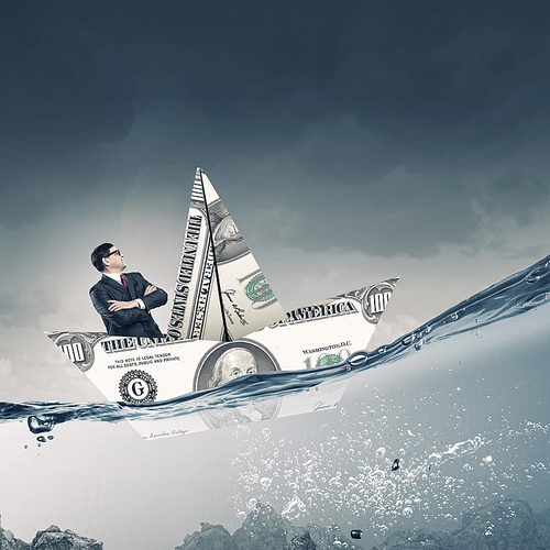 Businessman in ship of dollar banknote floating on water