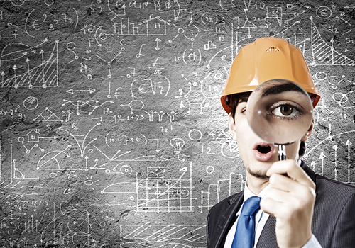 Young man architect against sketch background looking in magnifying glass