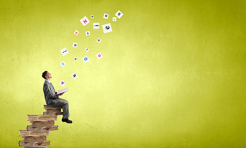 Young businessman sitting in pile of old books