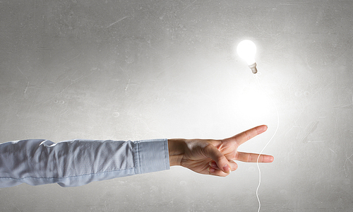 Businessman pointing with finger on glass glowing light bulb on dark background