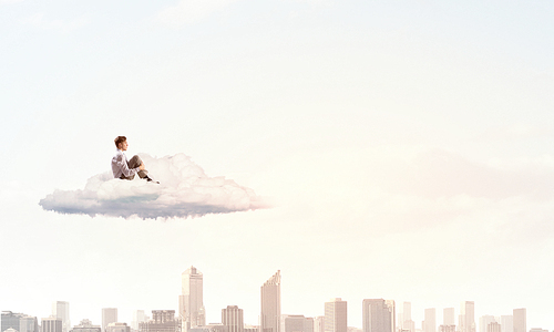 Depressed young businessman sitting alone on cloud high in sky