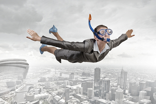 Young businesswoman in suit and diving mask flying in sky