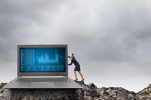 Young pretty businesswoman trying to move big laptop