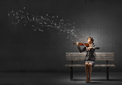 Young businesswoman sitting on bench and playing violin