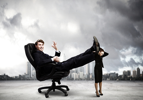 Young businessman sitting gin chair with legs on colleagues shoulders