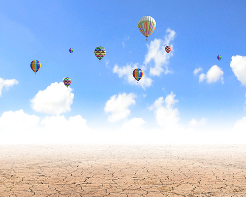 Colorful balloons flying high in blue sky above desert