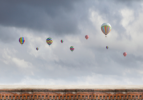 Colorful balloons flying high in grey sky