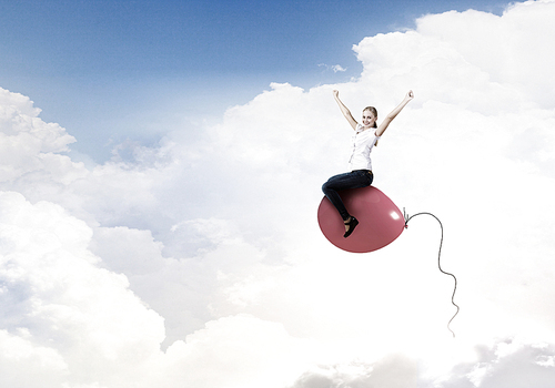 Young woman riding colorful balloon in sky