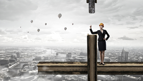 Young woman architect in hardhat standing on balk