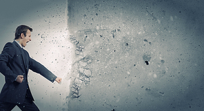 Businessman breaking stone wall with karate punch