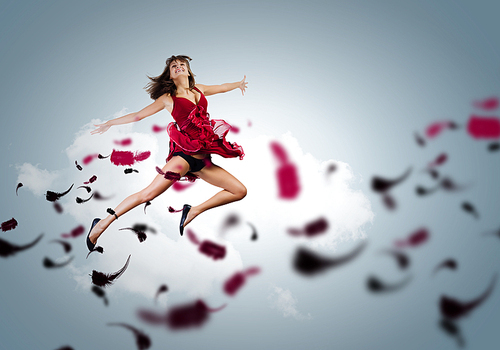 Young attractive woman in red dress jumping high