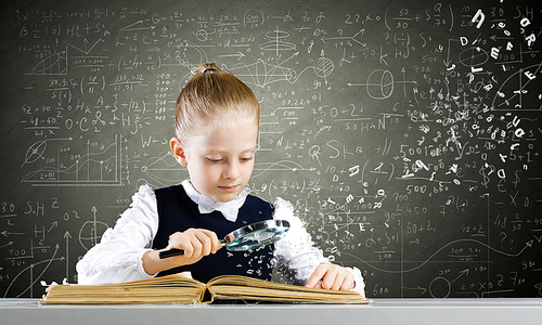 Schoolgirl examining opened book with magnifying glass