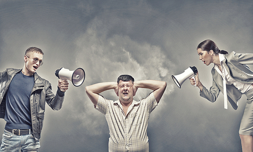 Furious people screaming agressively in megaphone at man