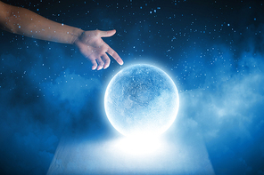Close up of human hand touching blue glowing moon