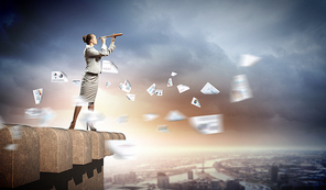 Image of businesswoman looking in telescope standing a top of building