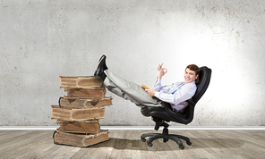 Young businessman sitting in chair with book in hands
