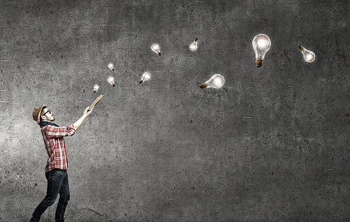 Hipster guy with book in hands and glass bulbs in air