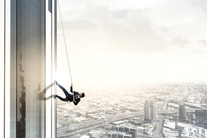 Determined businessman climbing building with help of rope