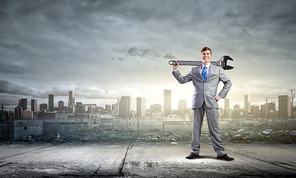 Young determined businessman with wrench in hands