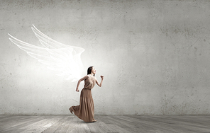 Attractive woman running with angel wings behind back