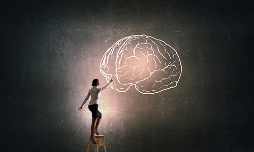 Businesswoman standing on chair and reaching brain concept above