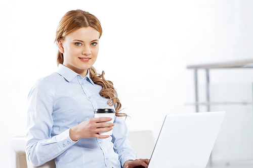 Young pretty businesswoman sitting and using laptop