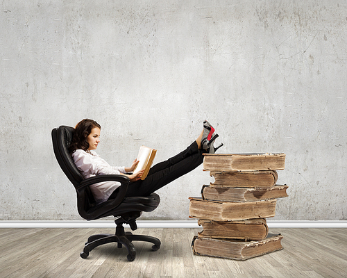 Young businesswoman sitting in chair and reading book