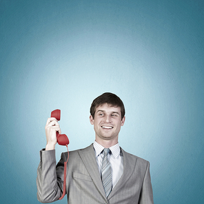 Handsome businessman talking on red phone handset