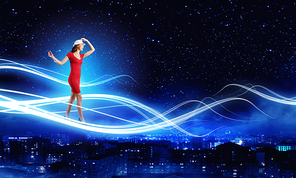 Young woman in red dress against night city background