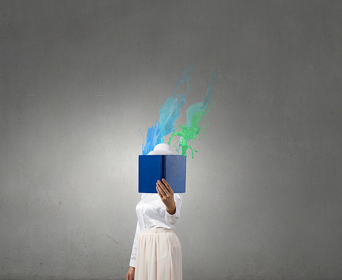 Woman with opened book against her face and colorful splashes coming from pages
