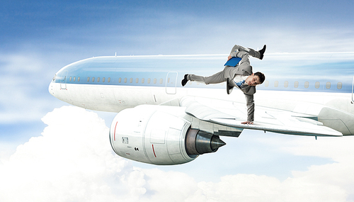 Active businessman making handstand on airplane wing
