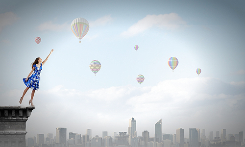 Happy young woman dreaming to fly in sky