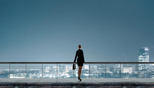 Back view of businesswoman standing on roof looking at city