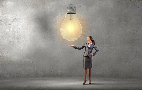 Smiling young businesswoman holding light bulb in palm