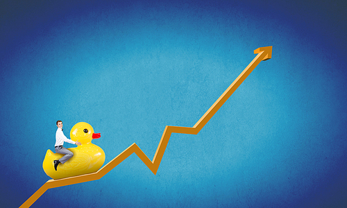 Young happy businessman riding yellow rubber duck on growing graph