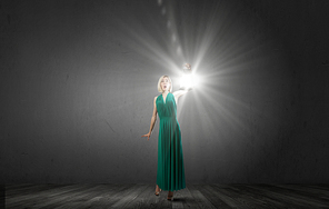 Young attractive woman in green dress with lantern walking in darkness