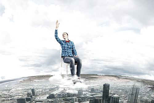 Young woman sitting in chair on cloud high in sky