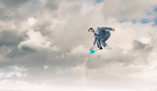 Young businessman standing on cloud and watering something below