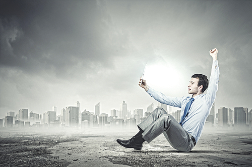 Young joyful handsome businessman using tablet pc